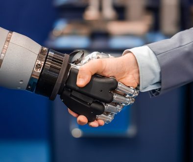 Hand of a businessman shaking hands with a Android robot.